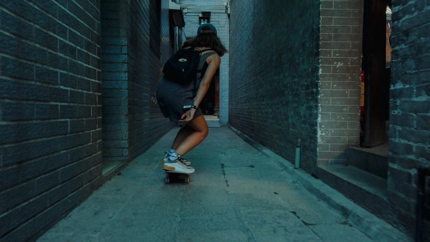 a girl riding her skateboard down a narrow alley way