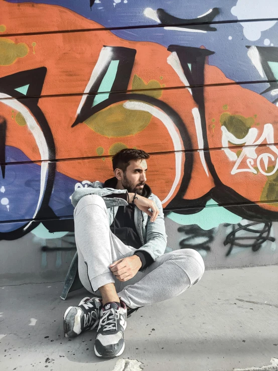 a man sitting in front of graffiti on the wall