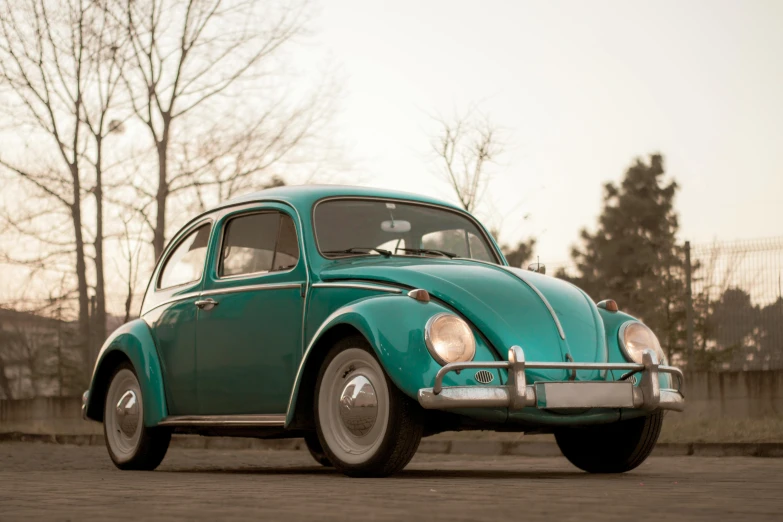 a very old green beetle parked in a parking lot