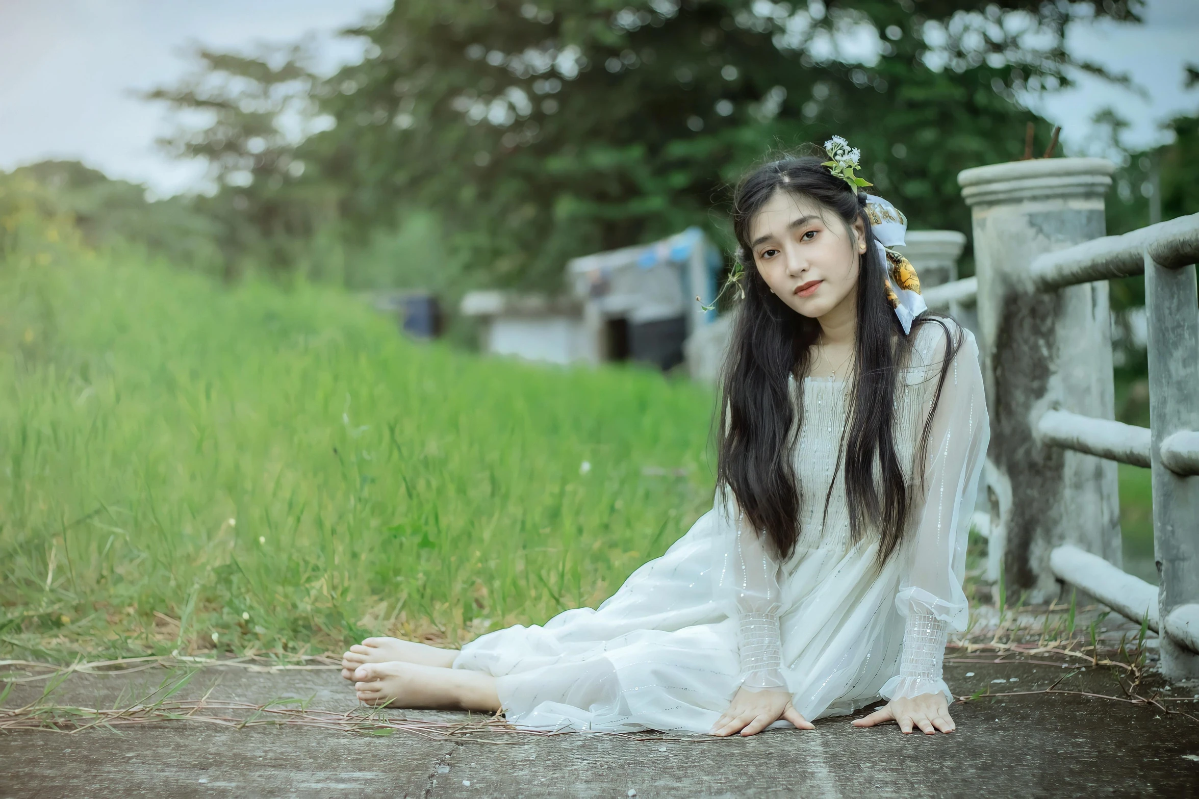 woman sitting on the ground in front of a fence