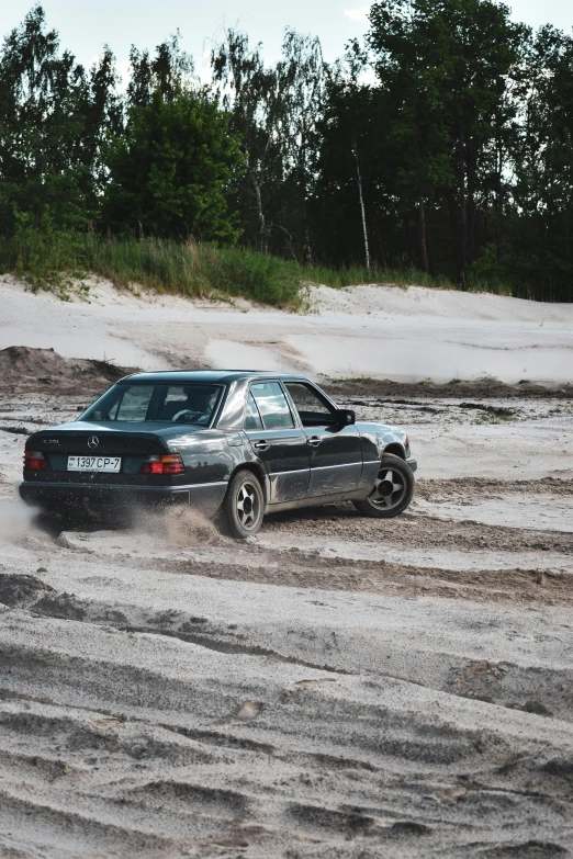 a man rides on a car while it drives in the mud