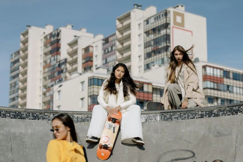 two woman sitting on top of a skateboard ramp