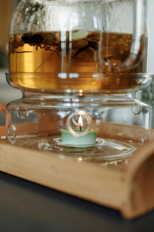 a glass container containing water with a candle on the top