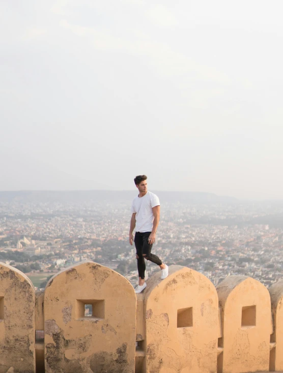 a young man standing on the top of a stone structure