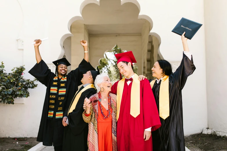 three people are wearing graduation gowns and holding their arms up in the air