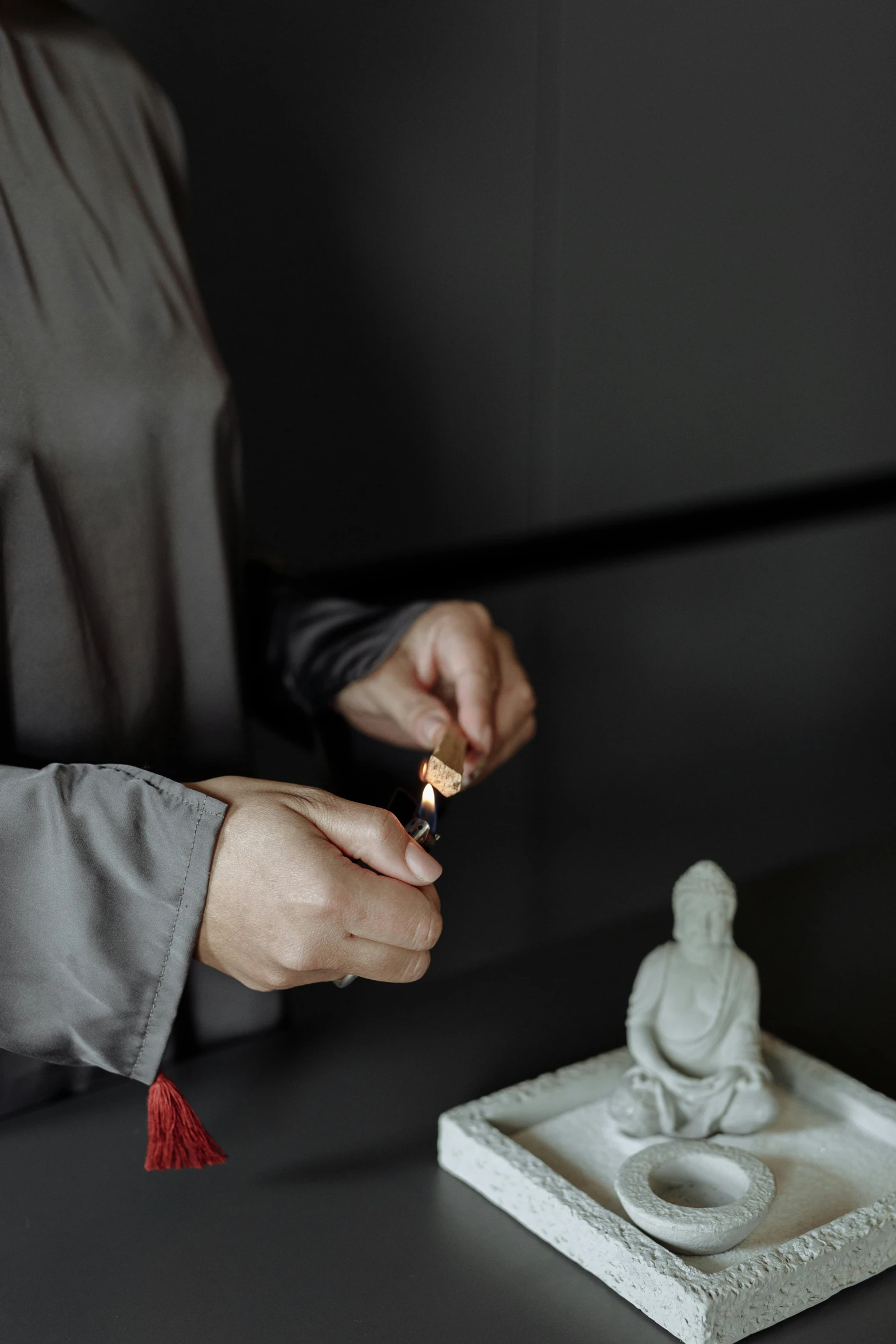 someone holding a candle with a small statue in the background