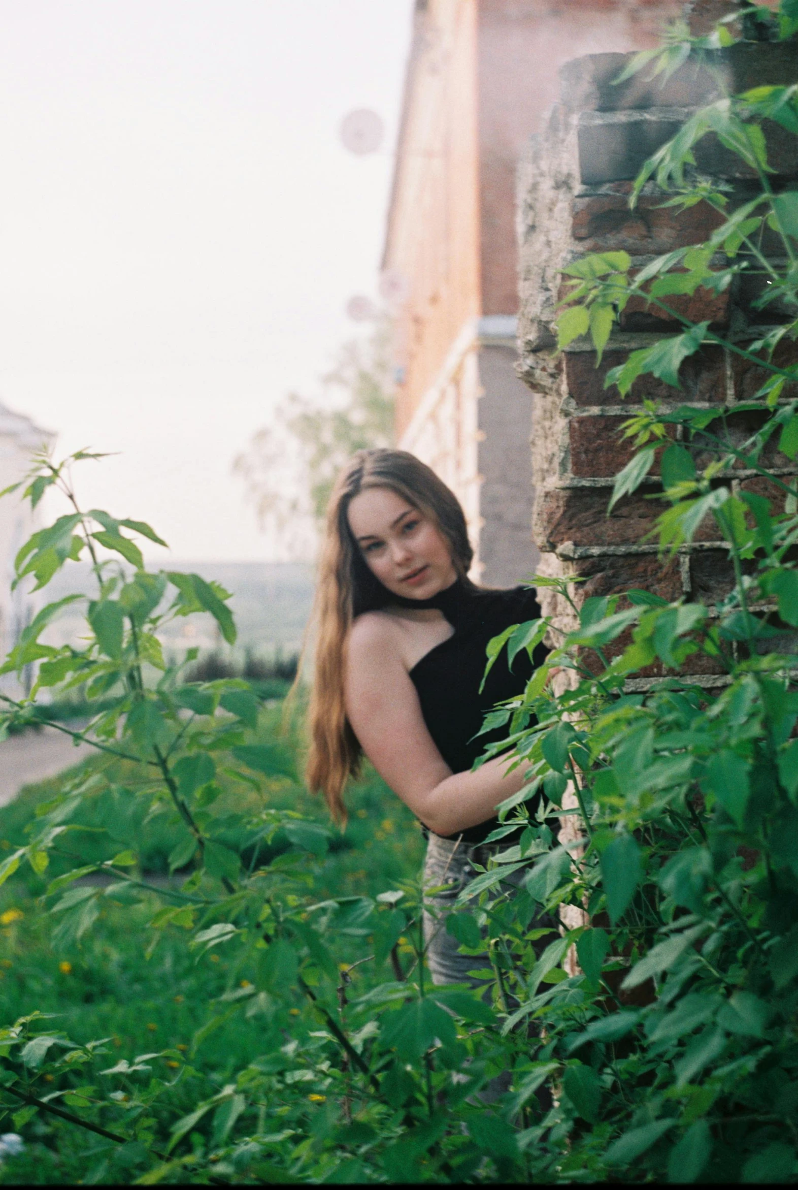 a woman wearing black posing for a po in a green environment