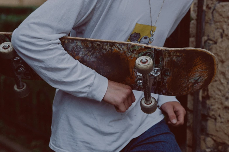 the man holding the skateboard is standing near the wall