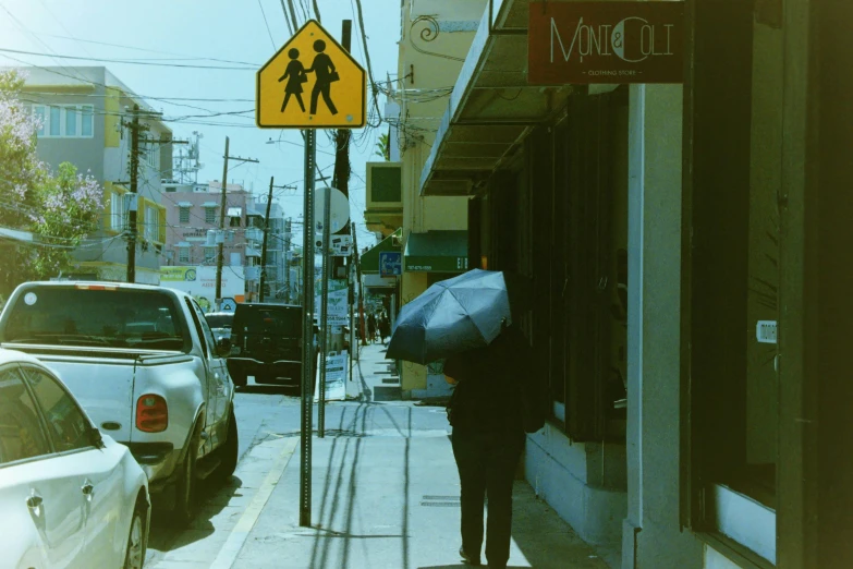 an older person standing with an umbrella on the sidewalk