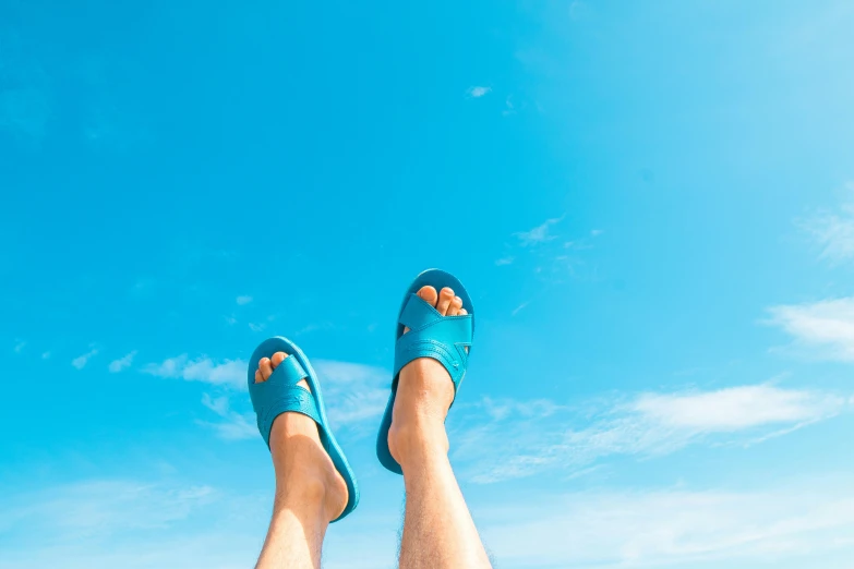 a pair of feet in blue flip flops overlooking the ocean