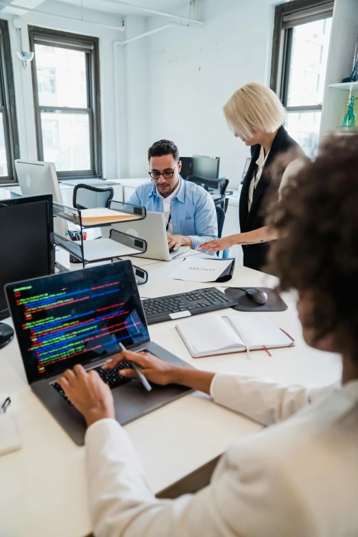 people at desk looking at different items on a laptop