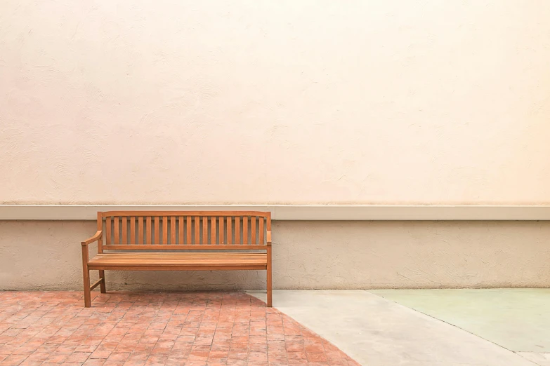 a wooden bench sitting next to a wall