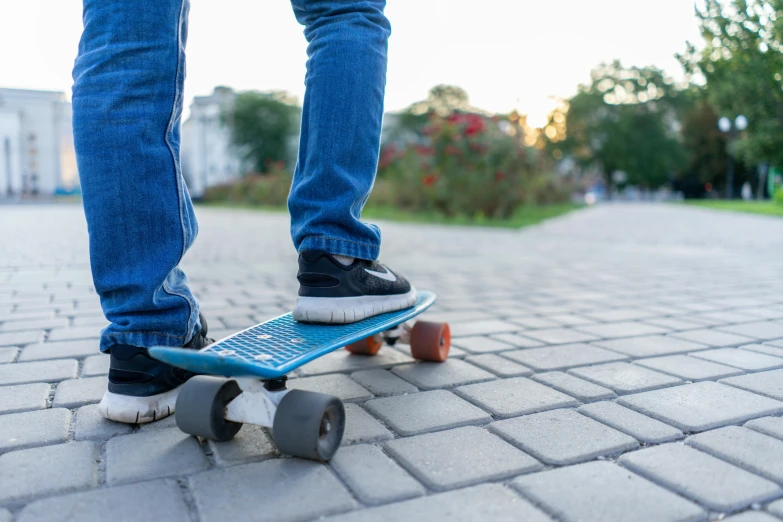 a person wearing blue jeans and black shoes standing on a skateboard