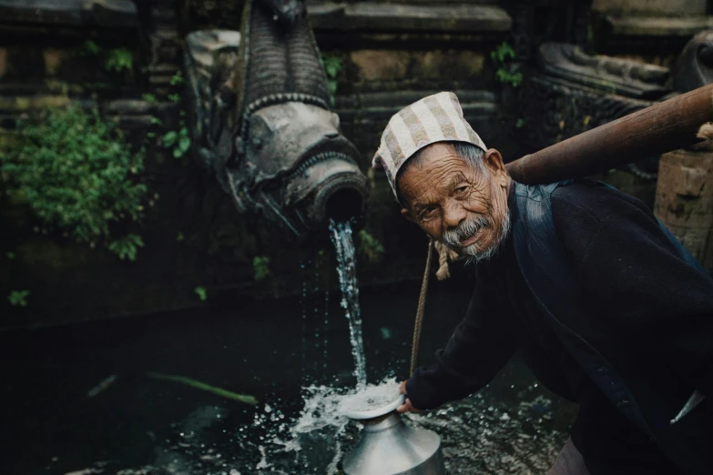 man wearing checkered cap preparing to pour water from water trough