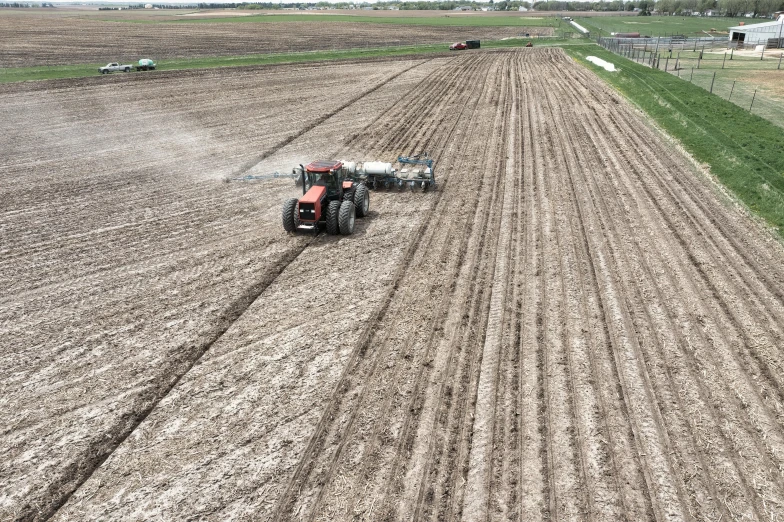 a large tractor plows a field with a person