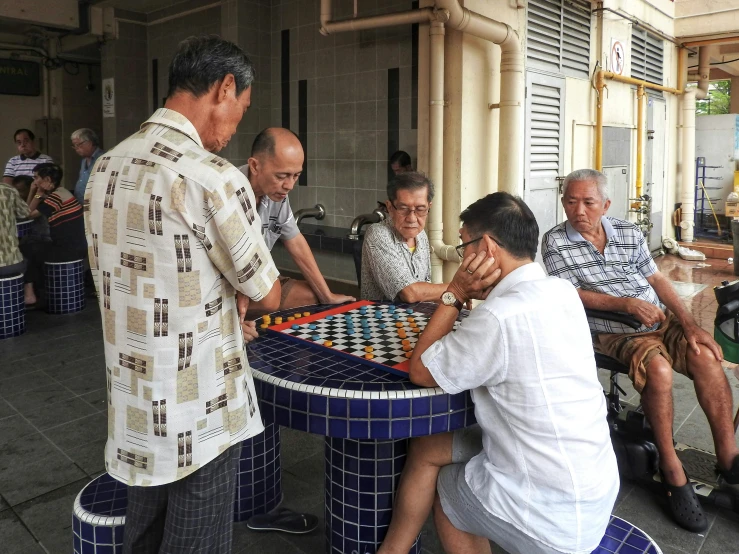 several people sit at table playing a game on the street