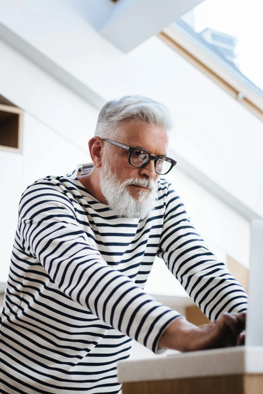 an older man using his laptop computer on a table