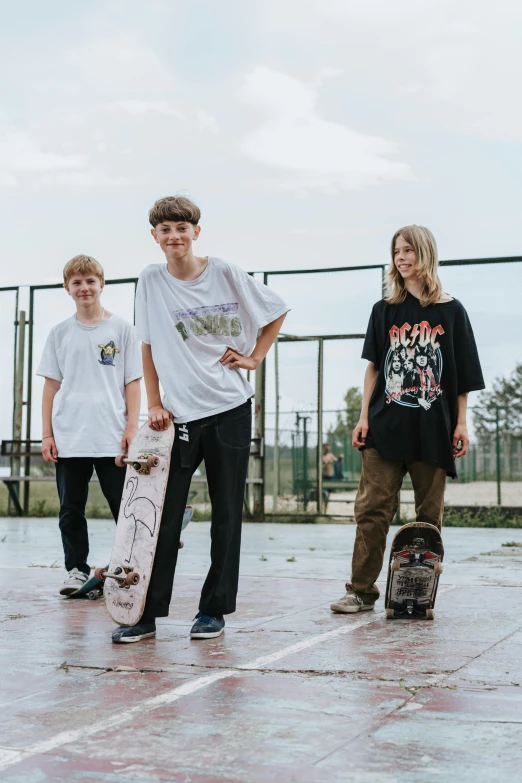 three young people standing in an empty court with one person holding a skateboard
