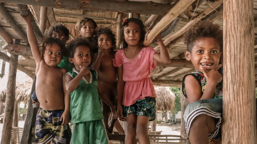 s with their arms up posing under a hut