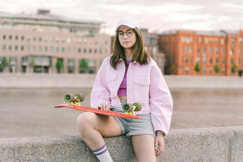 a girl sits with her skate board on a wall