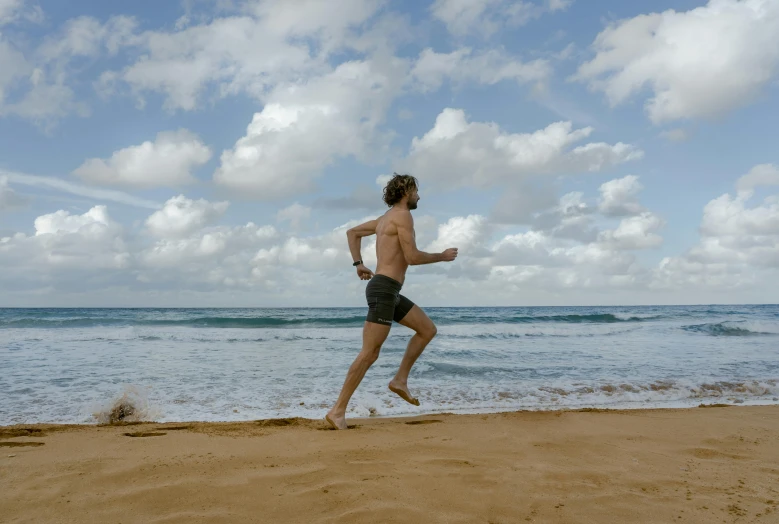 man running across the sand with a blue sky in background