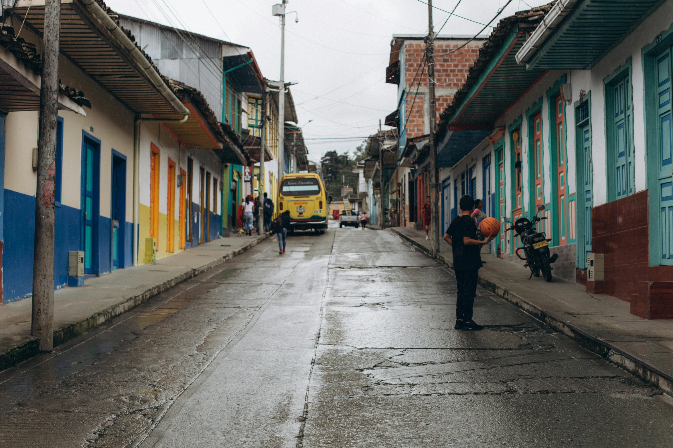 a street with people, buildings, and a bus in the background