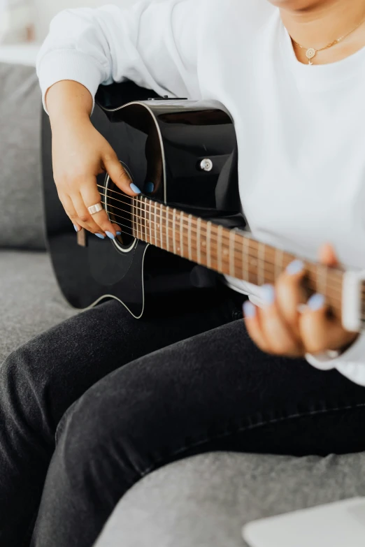 woman playing guitar sitting on couch in living room