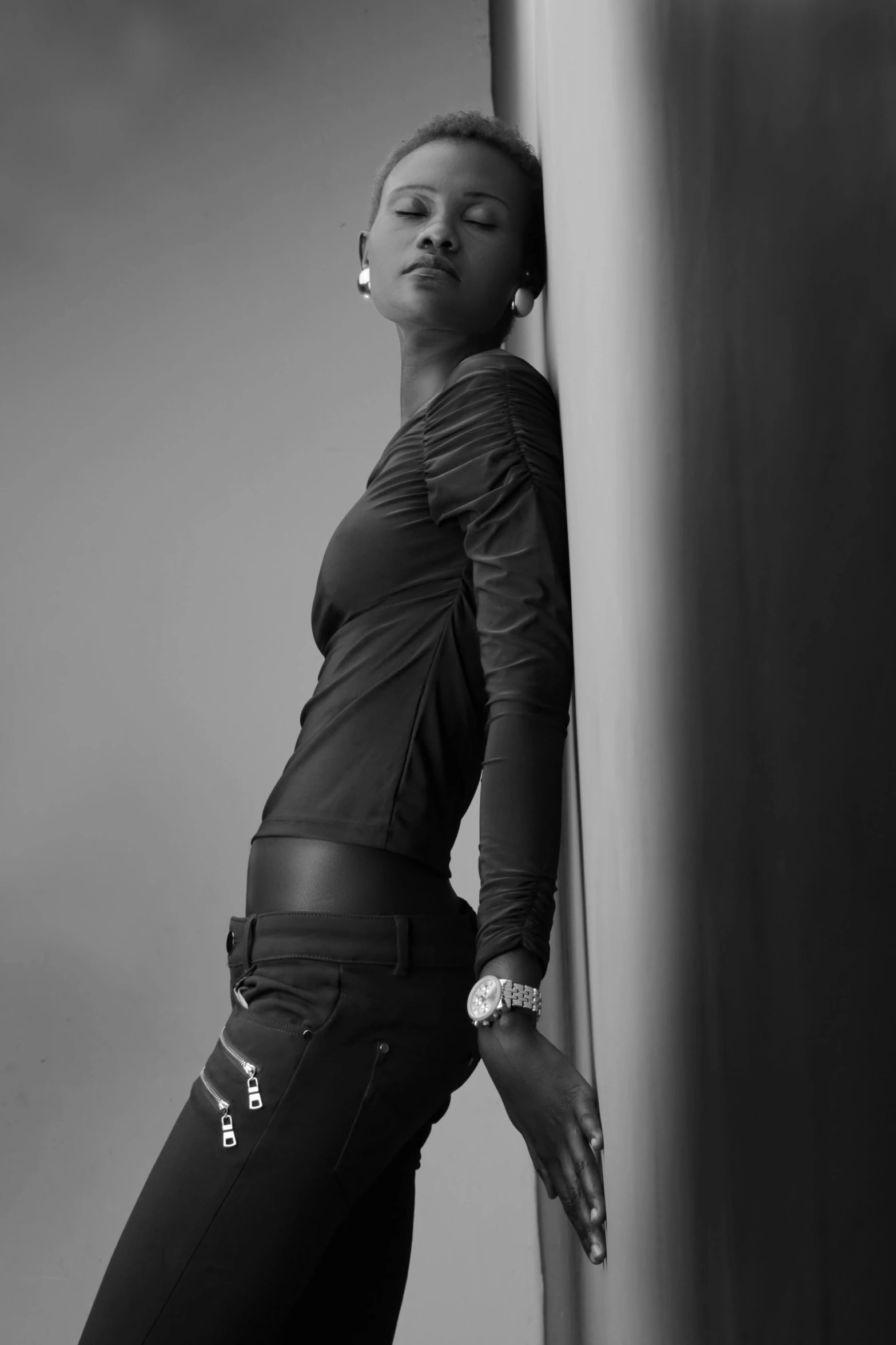 a black woman leaning against a pillar in a black and white po