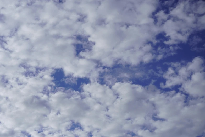 an airplane flies in the blue cloudy sky