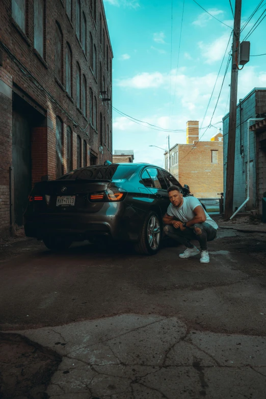 a person kneels next to a black car on the street