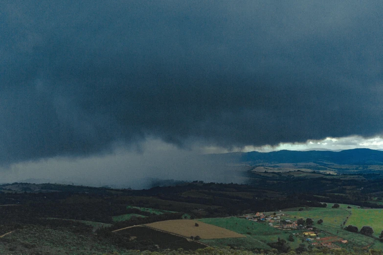 an ominous looking storm moving over a lush green country