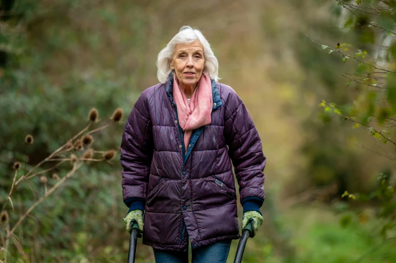 woman with walking stick walking in a forest