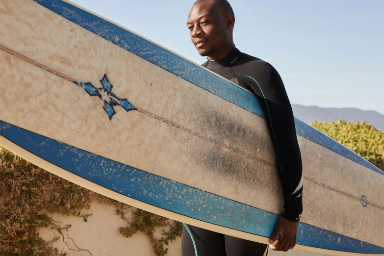 a man holding a surf board with mountains behind him