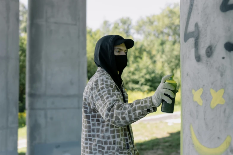 a man in a black mask spray painting the side of a column