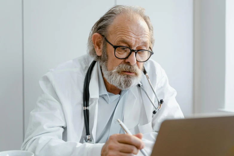 a man with a stethoscope sitting in front of his laptop