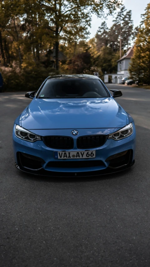 a blue sports car parked in front of trees