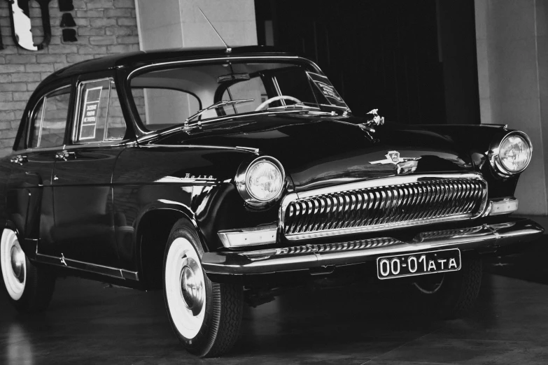 a vintage car is parked in front of a brick wall