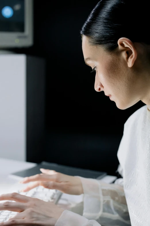 an asian woman working on a computer while typing