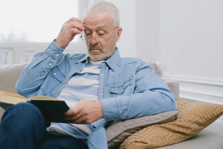 a man holding an open book while wearing glasses