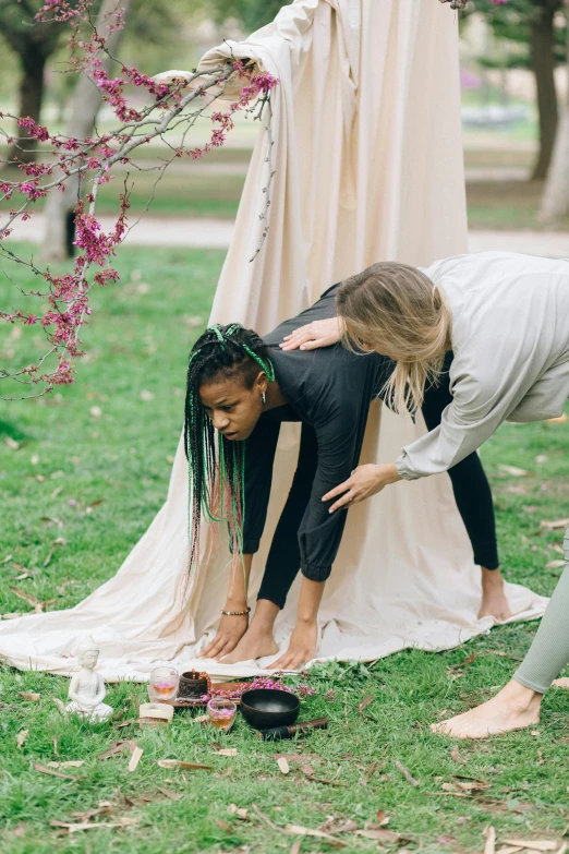 two girls standing in front of a cloth hanging in a field