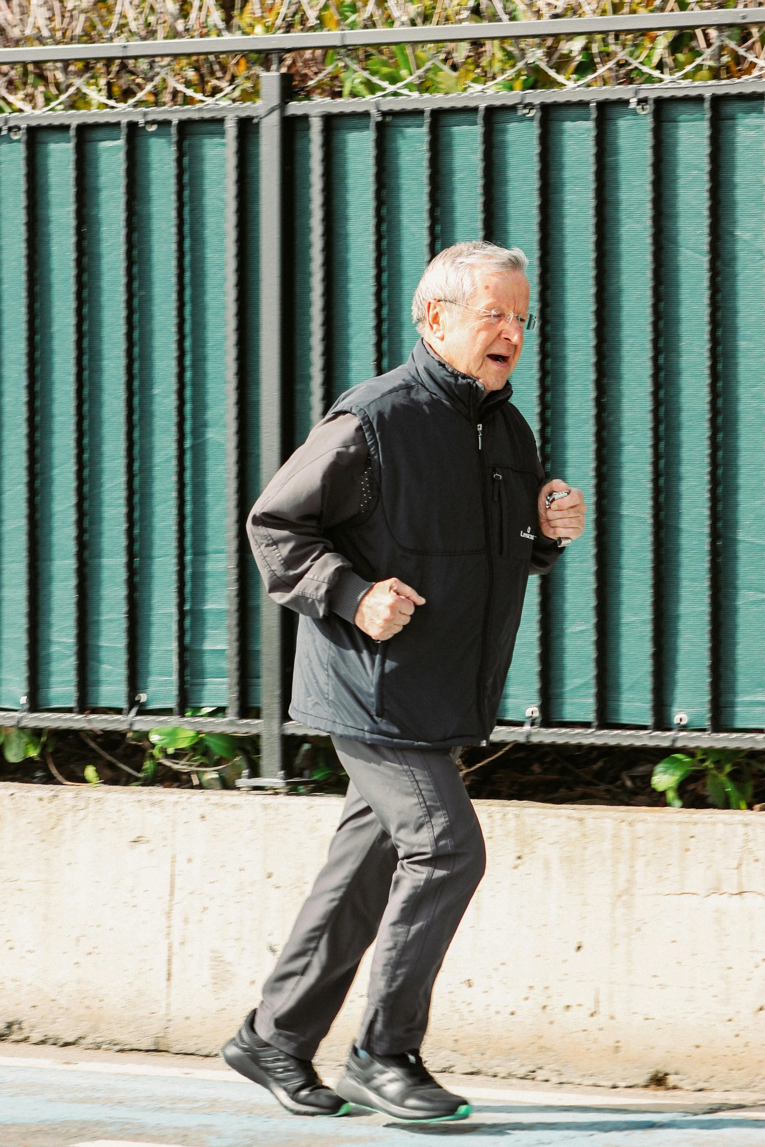 a man in a jacket and black pants is running by