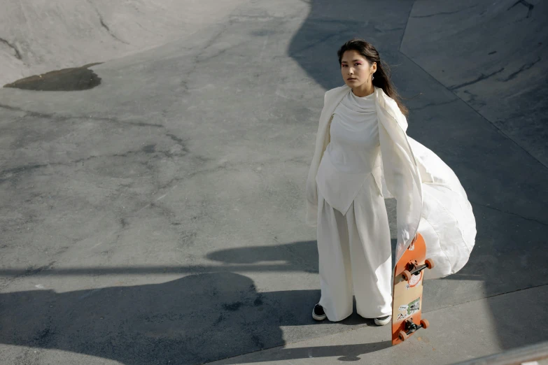 a woman is carrying her skateboard in an alley