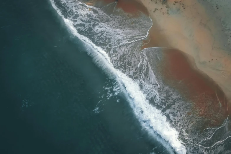 aerial view of an area of ocean, beach and waves