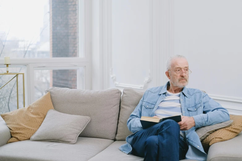 a man sitting on a couch reading a book