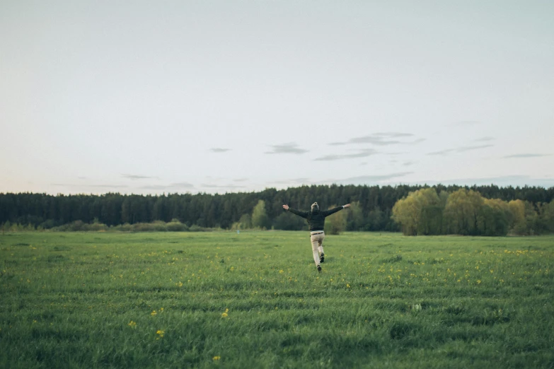 a person walking in a field, with trees in the background