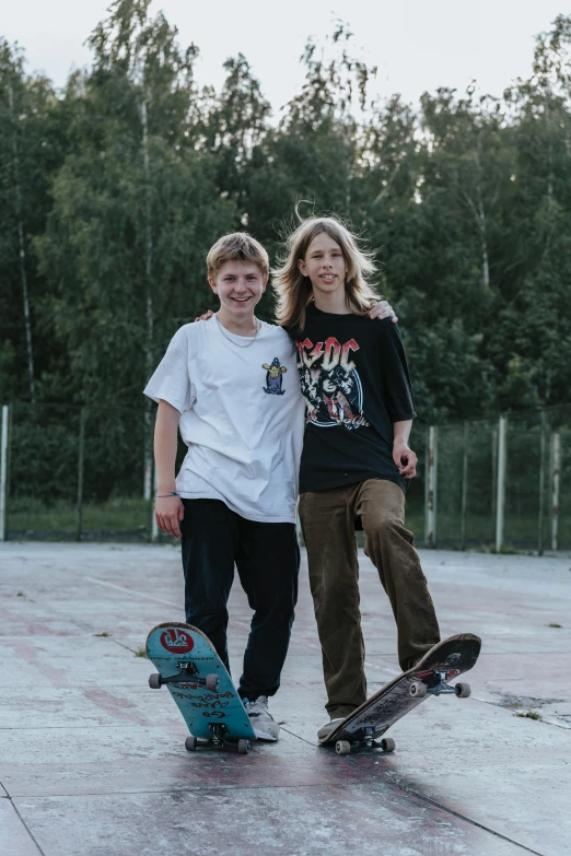 two teenage boys standing next to a skateboard