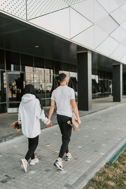 two people walking across a path near a building