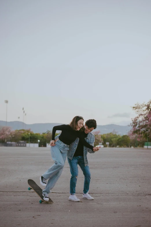 two s are in a parking lot playing on a skateboard