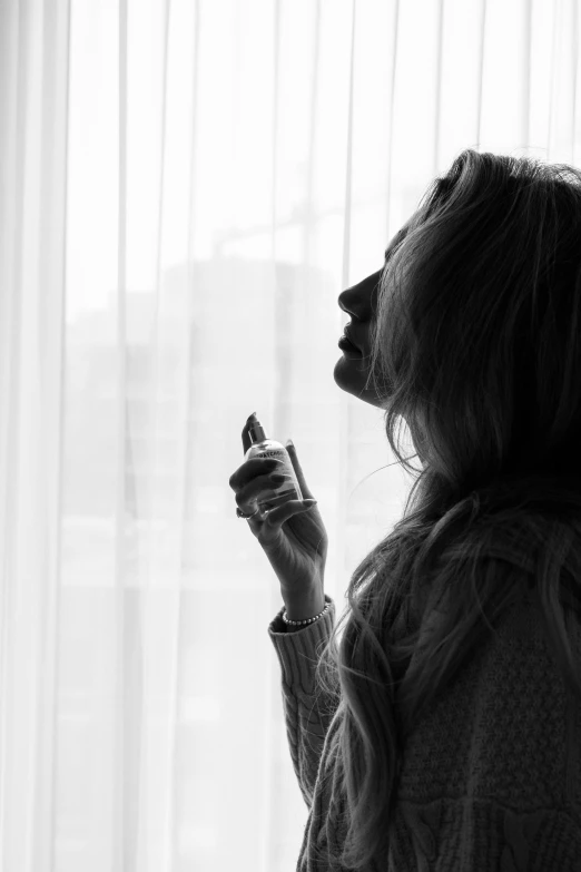 a woman wearing a sweater eating food in front of a window