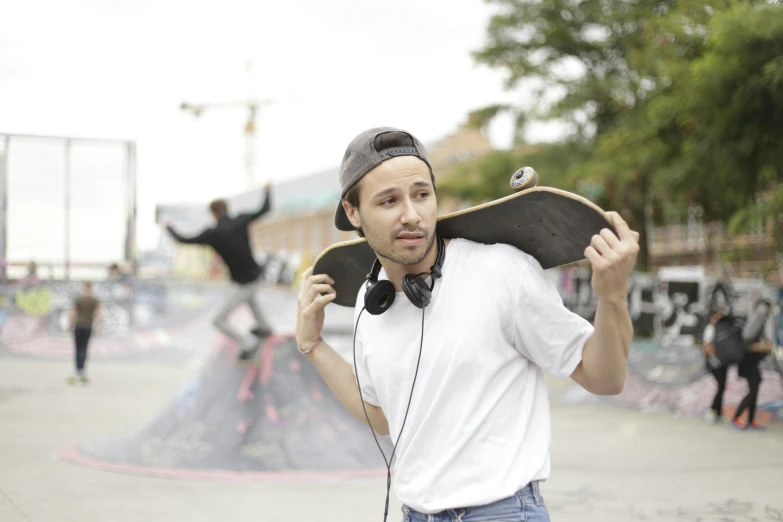 a man wearing headphones holds a skateboard in his hands